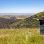 Land Trust of Santa Cruz County's Bryan Largay points north from the Rocks Ranch property towards Highway 101 hidden beneath the trees down below. Photo by Mike Kahn.