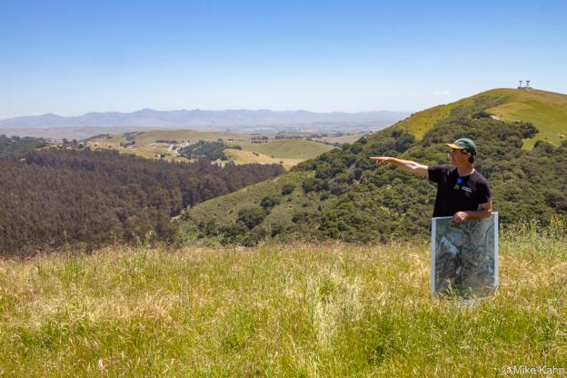 Land Trust of Santa Cruz County's Bryan Largay points north from the Rocks Ranch property towards Highway 101 hidden beneath the trees down below. Photo by Mike Kahn.
