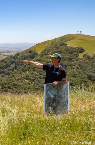 Land Trust of Santa Cruz County's Bryan Largay points north from the Rocks Ranch property towards Highway 101 hidden beneath the trees down below. Photo by Mike Kahn.