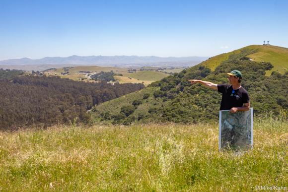 Land Trust of Santa Cruz County's Bryan Largay points north from the Rocks Ranch property towards Highway 101 hidden beneath the trees down below. Photo by Mike Kahn.