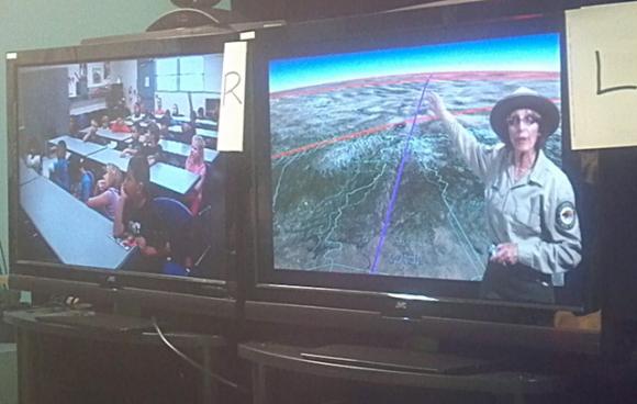 PORTS instructor Vonnie Lempke, right, delivers a videoconferenced lesson about butterflies to a second-grade classroom from a makeshift studio at Seacliff State Beach. The "L" and "R" signs help Lempke, standing off-camera, navigate the green screen as a TV meteorologist does.