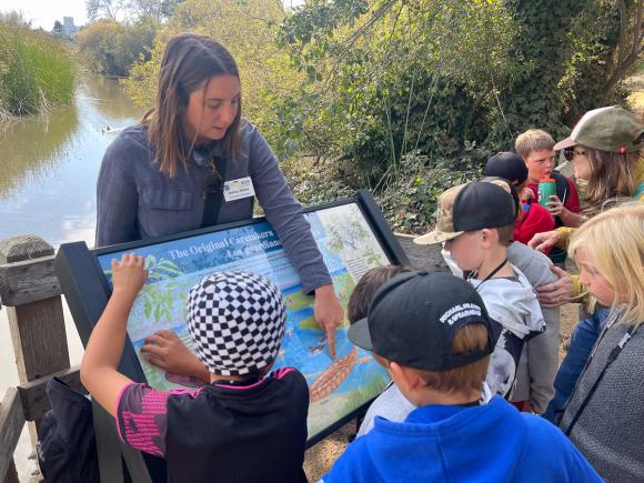 Jenny Rieke, Santa Cruz Museum of Natural History's Education Manager, shows students one of Neary Lagoon's new interpretive signs. Museum photo. 